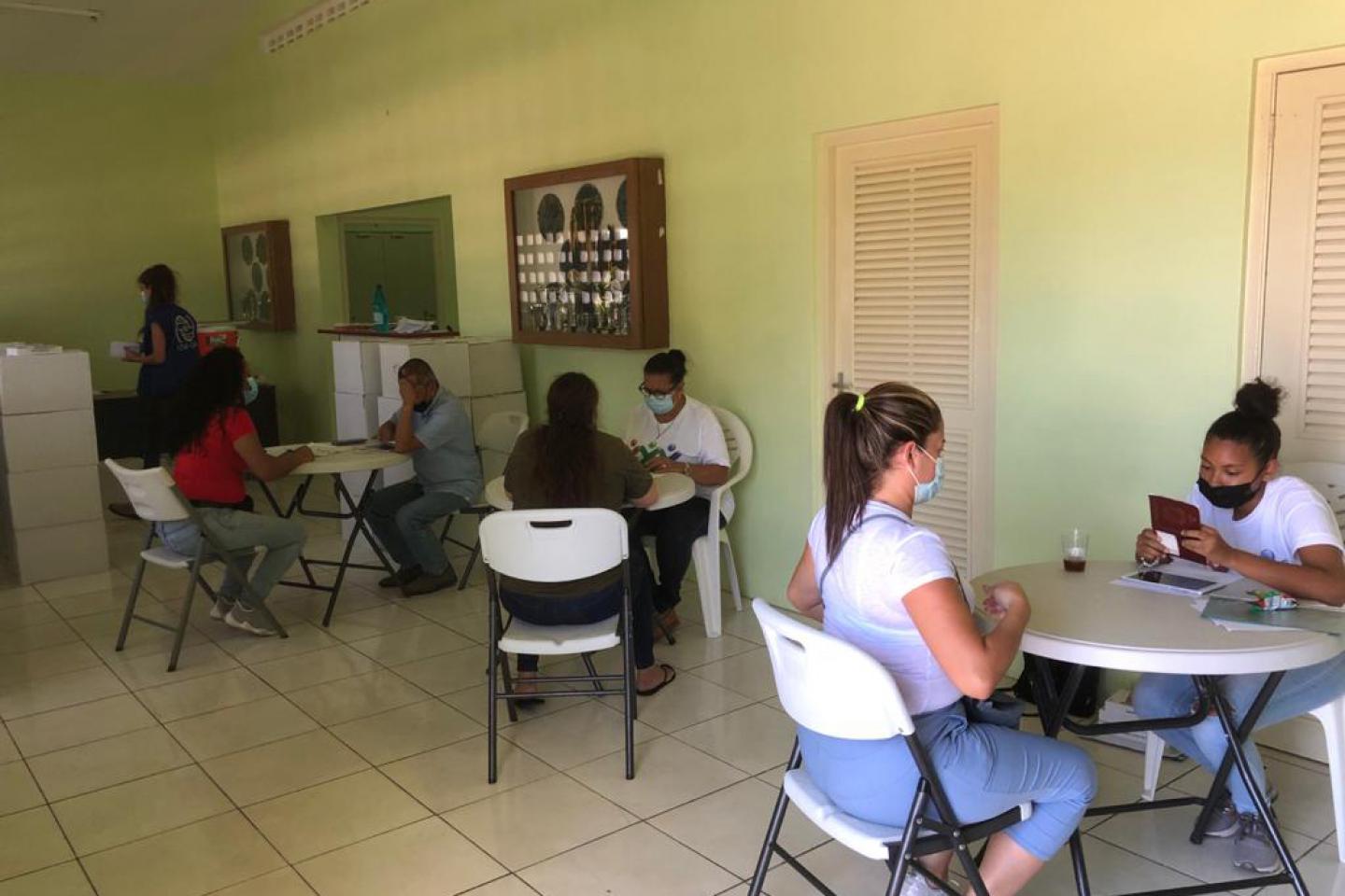 Persons sitting and talking at tables at Unidat di Bario