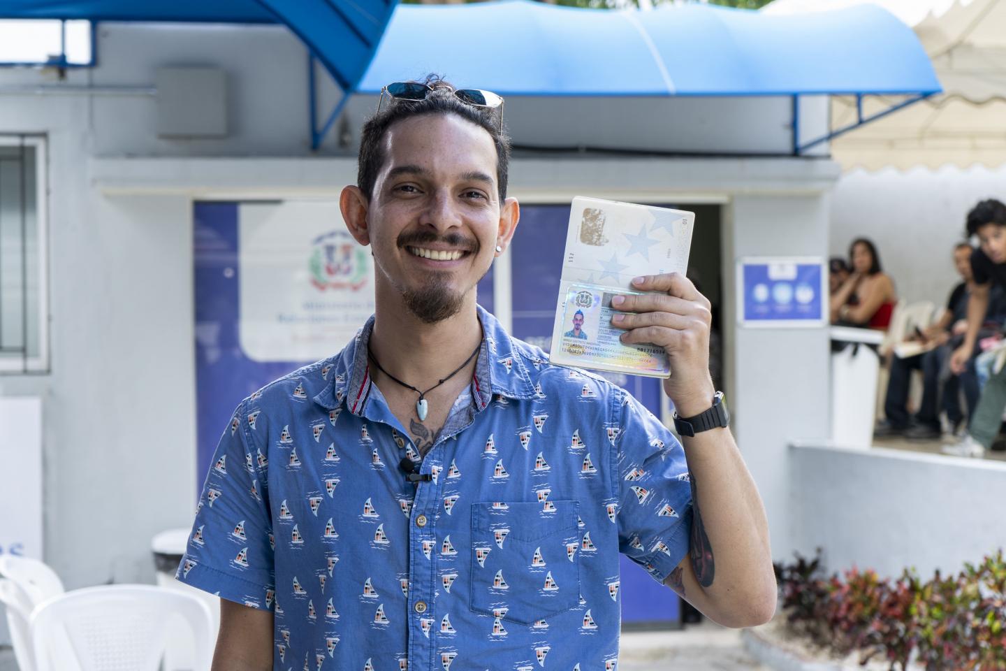 Joven venezolano posa para la foto junto a su pasaporte abierto en la página de la visa. 