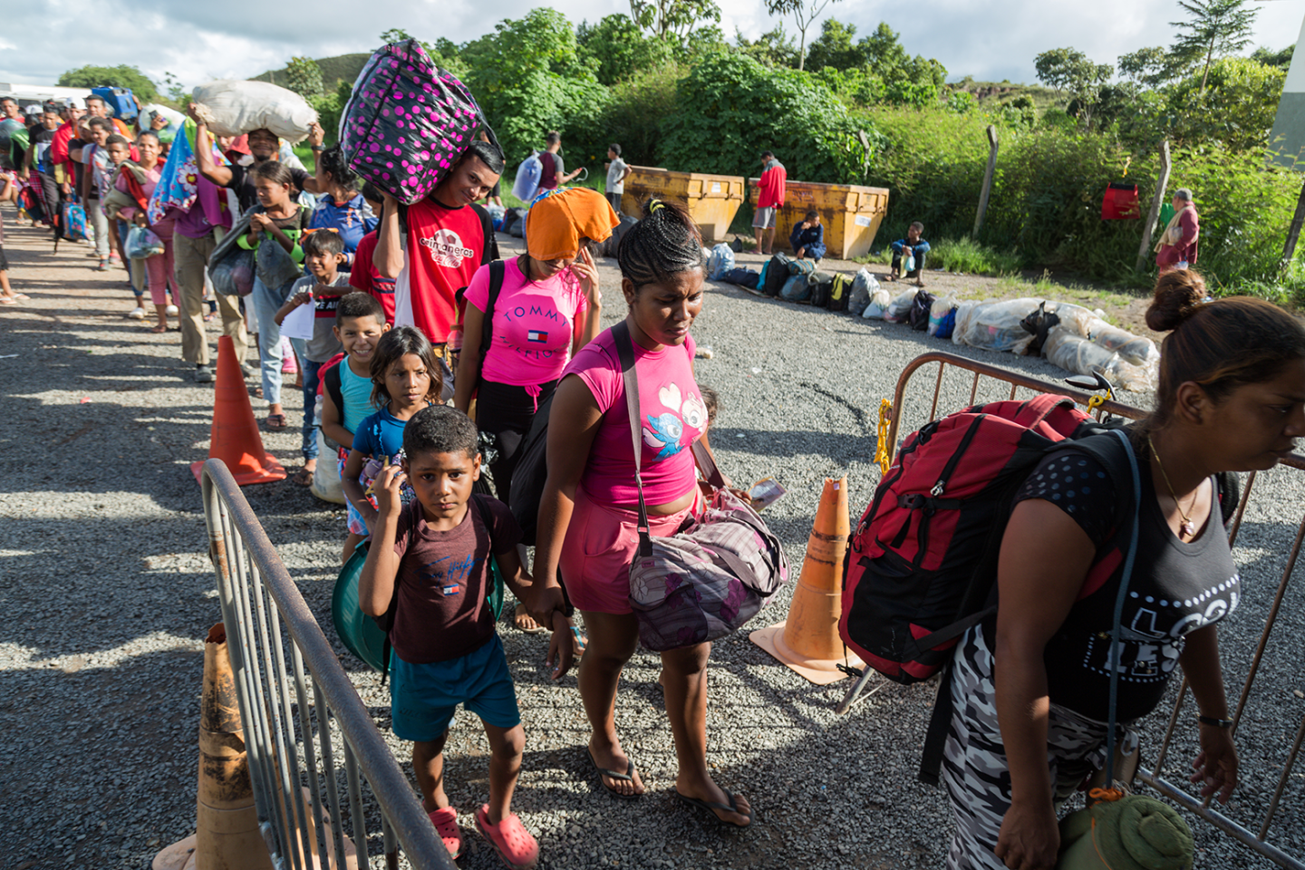 Personas refugiadas y migrantes de Venezuela ingresan a uno de los albergues que el gobierno de Brasil ha instalado en Pacaraima, con el apoyo de organizaciones internacionales, para ofrecerles protección (julio 2023). © R4V / Valmik Mota}